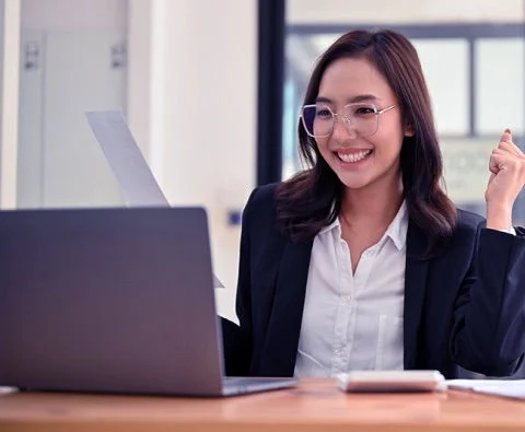Mulher sorrindo em frente ao computador com uso do relatório de crédito